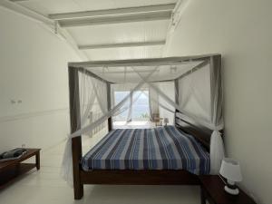 a bedroom with a canopy bed with a window at La maison sur la plage in Saint-Pierre