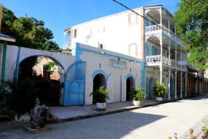 a white building with an archway and potted plants at hotel florita in Jacmel