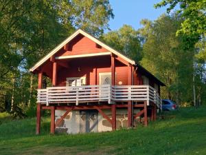 a red cabin with a balcony in a field at Rolsmo Norregård 16 in Linneryd