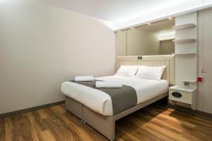 a bedroom with a bed with white walls and wooden floors at Point A Hotel London Shoreditch in London