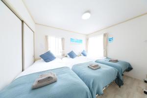 two beds in a room with blue sheets at Shonan Beach&Sun in Chigasaki