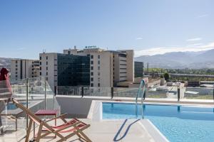 a balcony with a swimming pool and two chairs at Codomo Living Granada in Granada