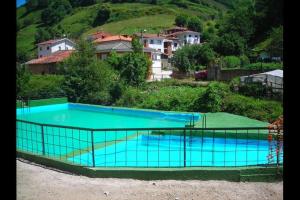 a large blue swimming pool on a hill with houses at La Cuadrina de Anton in Pajares