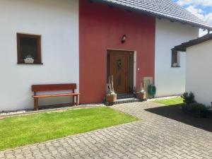 a red and white house with a bench and a door at Kašperky Apartmány in Kašperské Hory