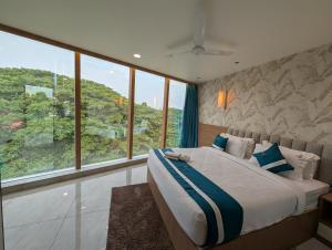 a bedroom with a large bed and large windows at The Aspire Hotel Guwahati in Guwahati