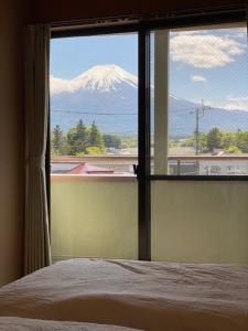a view of a snow covered mountain from a bedroom window at Guest House KURA 776 Mt Fuji View and 1 min to Gekkoji Station in Fujiyoshida