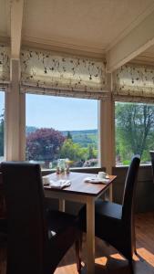 a dining room table with chairs and a large window at Sawrey House in Near Sawrey