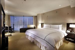 a bedroom with a large white bed and a desk at K Hotel Taipei Dunnan in Taipei