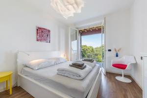 a white bedroom with a white bed and a red chair at Casa 3 Rose Lake View and Pool in Toscolano Maderno +16 photos
