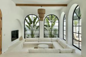 a living room with a white couch and large windows at Melrose x The Young Villas in Uluwatu