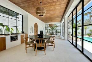 a dining room with a table and chairs and a pool at Melrose x The Young Villas in Uluwatu