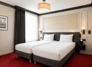 a bedroom with a large white bed and a window at Hôtel Le Montmartre Saint Pierre in Paris