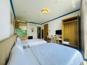 a hotel room with two beds and a desk at Lighthouse Hotel & Apartment Phan rang in Kinh Dinh