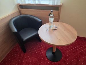 ein Tisch mit einer Flasche Wasser und einem schwarzen Stuhl in der Unterkunft Hotel Zum Kellermann in Grafenau