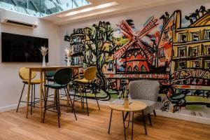a room with chairs and a large painting on the wall at Hôtel Le Montmartre Saint Pierre in Paris