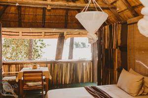 a bedroom with a bed and a table and a desk at Epupa Falls Lodge in Epupa