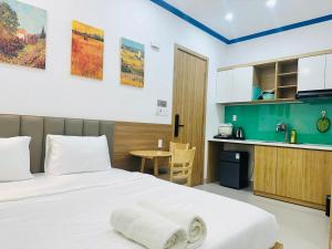 a bedroom with a white bed and a kitchen at Lighthouse Hotel & Apartment Phan rang in Kinh Dinh