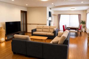 a living room with couches and a flat screen tv at Sumomo in Takayama