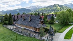 an old house in a field with mountains in the background at Willa Rajka in Zakopane