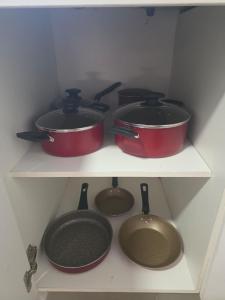 four pots and pans on a shelf in a kitchen at Duplex en Luque in Zarate Isla