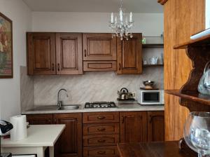 Casa Vacanze CIMMO في Tavernole sul Mella: مطبخ بخزائن خشبية وحوض غسيل وميكروويف