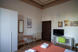 a room with a bed and a table and a television at Casa di Alfredo Affittacamere in Siena