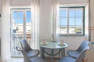 a table and chairs in a room with windows at Casa Lori Albufeira in Albufeira +11 photos