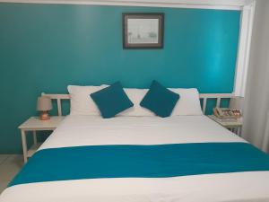 a blue bedroom with a white bed with blue walls at Melrose Beach Apartments Inc in Bridgetown