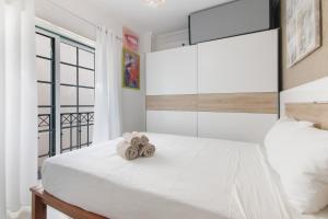a bedroom with a white bed with a large window at Casa Lori Albufeira in Albufeira