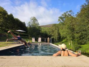 two people are jumping into a swimming pool at Casa Rio D'Além in Melgaço