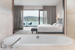 a bath tub in a hotel room with a bedroom at Linde Villas in Maria Wörth