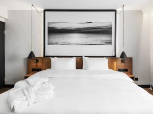 a bedroom with a white bed with a picture on the wall at Mercure Klaipėda City Hotel, Meetings, Events, Restaurant & Bar - Accor Group in Klaipėda