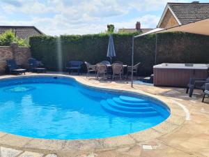 a swimming pool with chairs and a table and an umbrella at The Nest in Aylsham