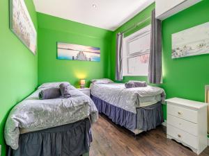 a green bedroom with two beds and a window at By The Beach- Uk31201 in Downderry