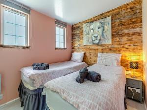 two beds in a room with wooden walls and windows at By The Beach- Uk31201 in Downderry