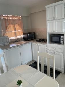 a kitchen with white cabinets and a table and chairs at Melrose Beach Apartments Inc in Bridgetown