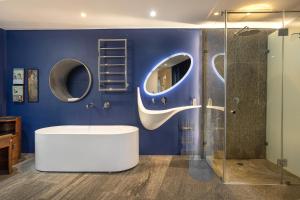 a bathroom with a white tub and a blue wall at 17 Marine - Apt 103 - Private Hot Tub & Garden in Hermanus +24 photos