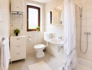 a white bathroom with a toilet and a sink at Apartments Mohar II in Baška