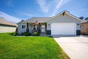 a house with a white garage and an american flag at Prairie Falls in Post Falls