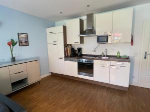 a kitchen with white cabinets and a stove top oven at Ferienwohnung Meding am See in Schondorf am Ammersee