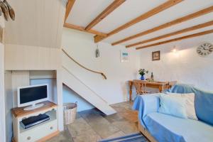 a living room with a blue couch and a tv at 1 Bed in Ruan Minor oc-rencot in Ruan Minor