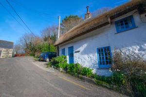 a white building with blue windows and a street at 1 Bed in Ruan Minor oc-rencot in Ruan Minor