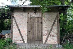a brick out house with a wooden door at Herrenhaus Libnow in Murchin