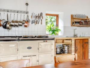a kitchen with white cabinets and a wooden table at The Barn - Uk51594 in Grantham