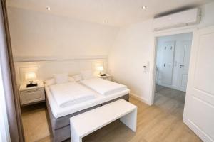 a white bedroom with a bed and a table at Heidetraum - Modernes Ferienhaus in der Lüneburger Heide in Soltau