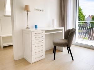 a white desk and chair in a room with a window at Heidetraum - Modernes Ferienhaus in der Lüneburger Heide in Soltau