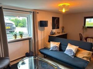 a living room with a blue couch and a glass table at Haus Annemiek in Winterberg