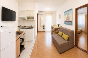 a kitchen and a living room with a couch and a table at Apartments Mohar III in Baška