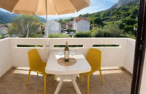 a white table with chairs and an umbrella on a balcony at Apartments Mohar III in Baška