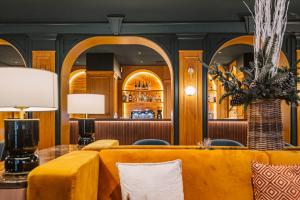 a lobby with yellow couches and a bar at Grand Hotel Bellevue - Grand Place in Lille